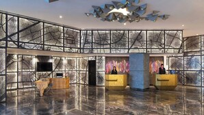 A lobby with a reception desk, seating area, and a large wall with a map design. - Renaissance Ahmedabad Hotel (Ahmedabad)