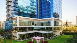 A modern building with a glass facade, a rooftop terrace, and a central courtyard with seating. - Renaissance Ahmedabad Hotel (Ahmedabad)