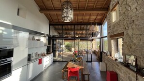 A modern kitchen with a wooden ceiling, large windows, and a dining area with a table and chairs. - Le Pallier + extension (DIO-ET-VALQUIERES)