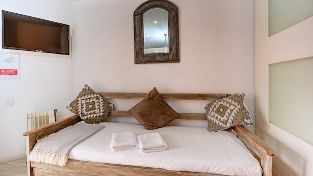 A bed with a wooden frame, white linens, and two pillows. - Inn Bairro Alto Bed & Breakfast (Lisbon)