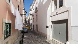 A narrow cobblestone street with buildings on either side, a trolley, and a car parked on the right. - Chiado Studios By Lu Holidays (Lisbon)