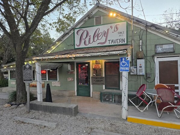 Le Riley's Tavern se distingue par sa façade verte, son panneau indicateur, son entrée accessible aux personnes à mobilité réduite, ses places assises en plein air et son panneau de signalisation pour le stationnement.