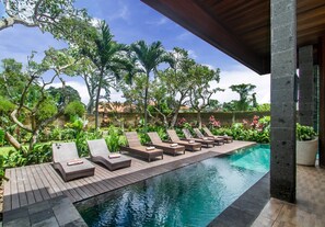 A pool area with lounge chairs and a wooden deck. - Sarin Ubud Suites (Ubud)