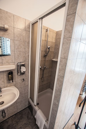 A bathroom with a shower, sink, and hand dryer. - Pension Hargita (Vienna)