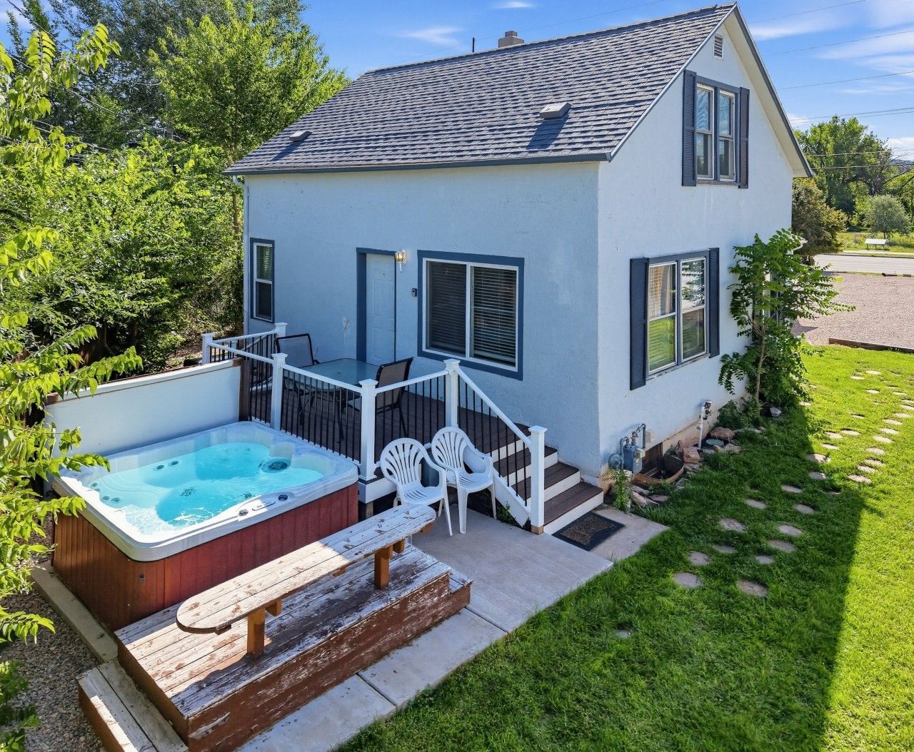 Ein zweigeschossiges Haus mit Whirlpool, Sitzgelegenheit im Freien und einer Treppe, die zur Terrasse führt.