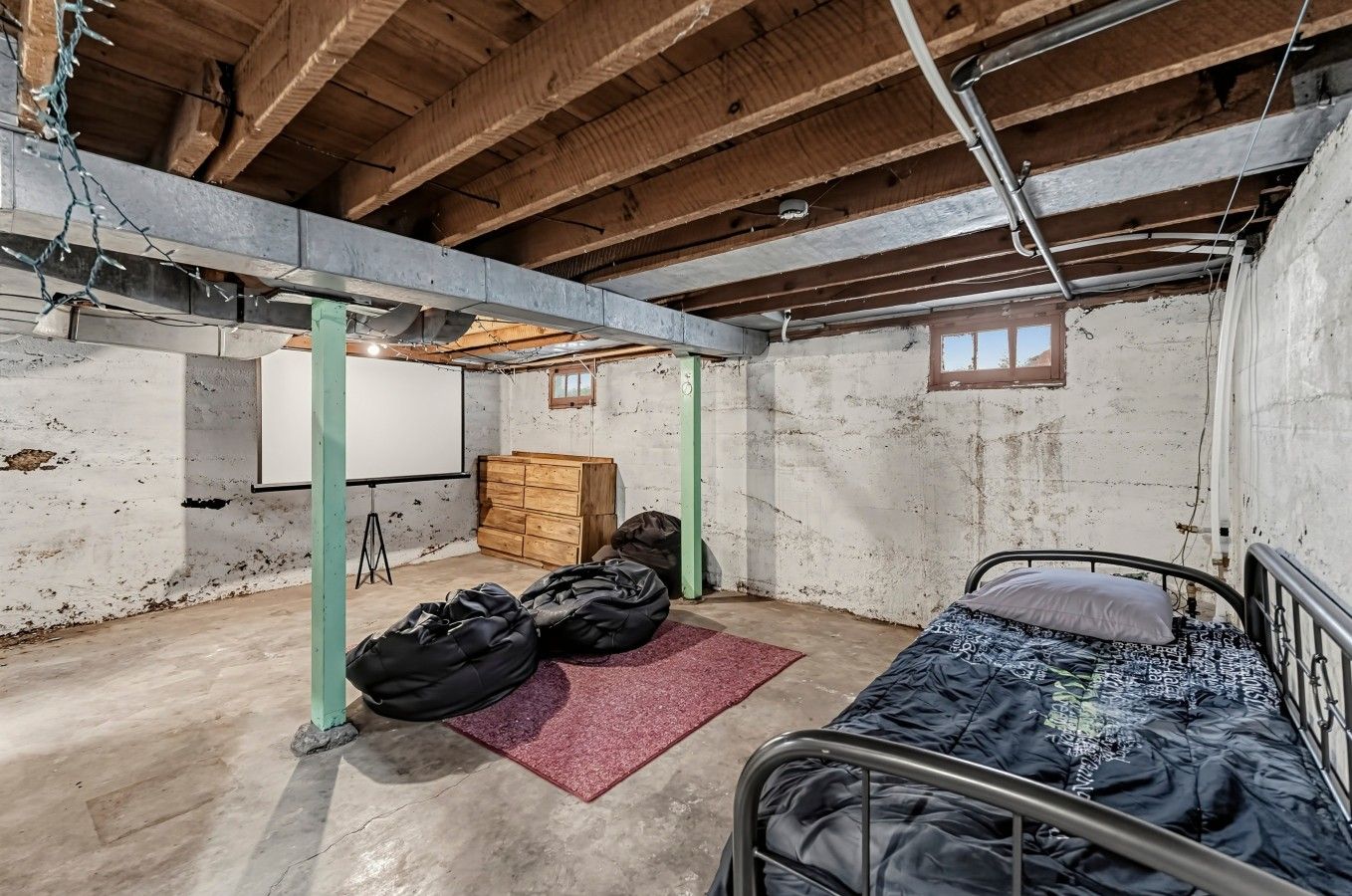 Una habitación con cama, pantalla de proyector y un armario de madera.