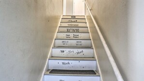 Una scala i cui gradini sono contrassegnati da frasi motivazionali come 'LOVE', 'CHOCOLATE', 'YOU', 'PLAYS', 'WORK' e 'HARD'.