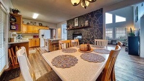 Cocina amplia con armarios de madera, una isla central y un comedor con mesa para cuatro.