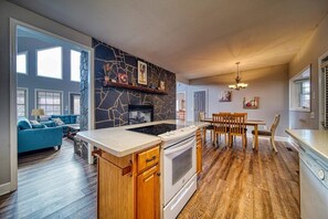 Eine moderne Küche mit Steinrückwand, einem eingebauten Herd und einem Essbereich mit Holztischen und einer Tischplatte.