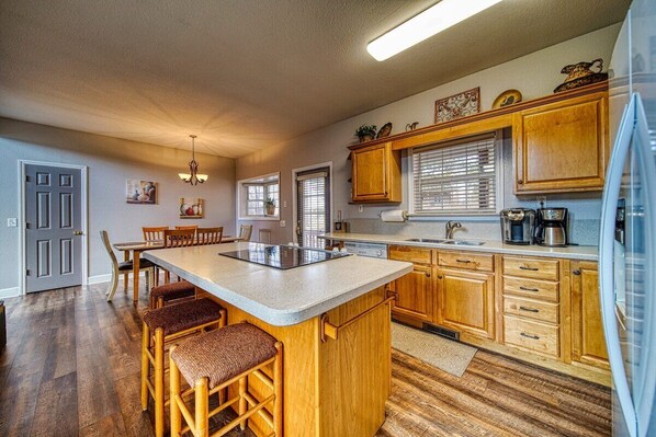 A kitchen with wooden cabinets, a central island, and a dining area with chairs. - Mossy Oaks Lodge-Fireplace-Pool Table (Hiawassee)