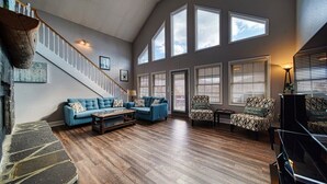 Una sala de estar amplia con escalera, ventanas grandes y chimenea.