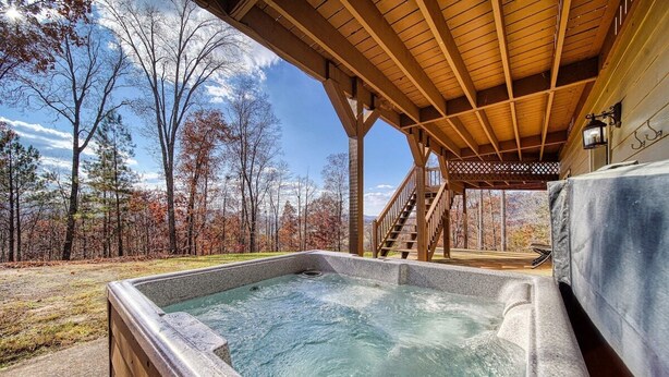 Ein Whirlpool unter einer Holzpergola mit Blick auf Bäume und einen klaren Himmel.
