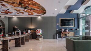 A spacious lobby with a high ceiling, a reception desk, seating area, and a large wall-mounted television. - The Green Escape Suite (Mexico City)