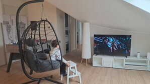 Ein Wohnzimmer mit einem Hängekorbstuhl, einem Fernseher und einer weißen Unterhaltungsanlage.