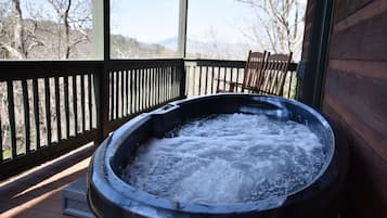A hot tub on a wooden deck with a view of mountains.