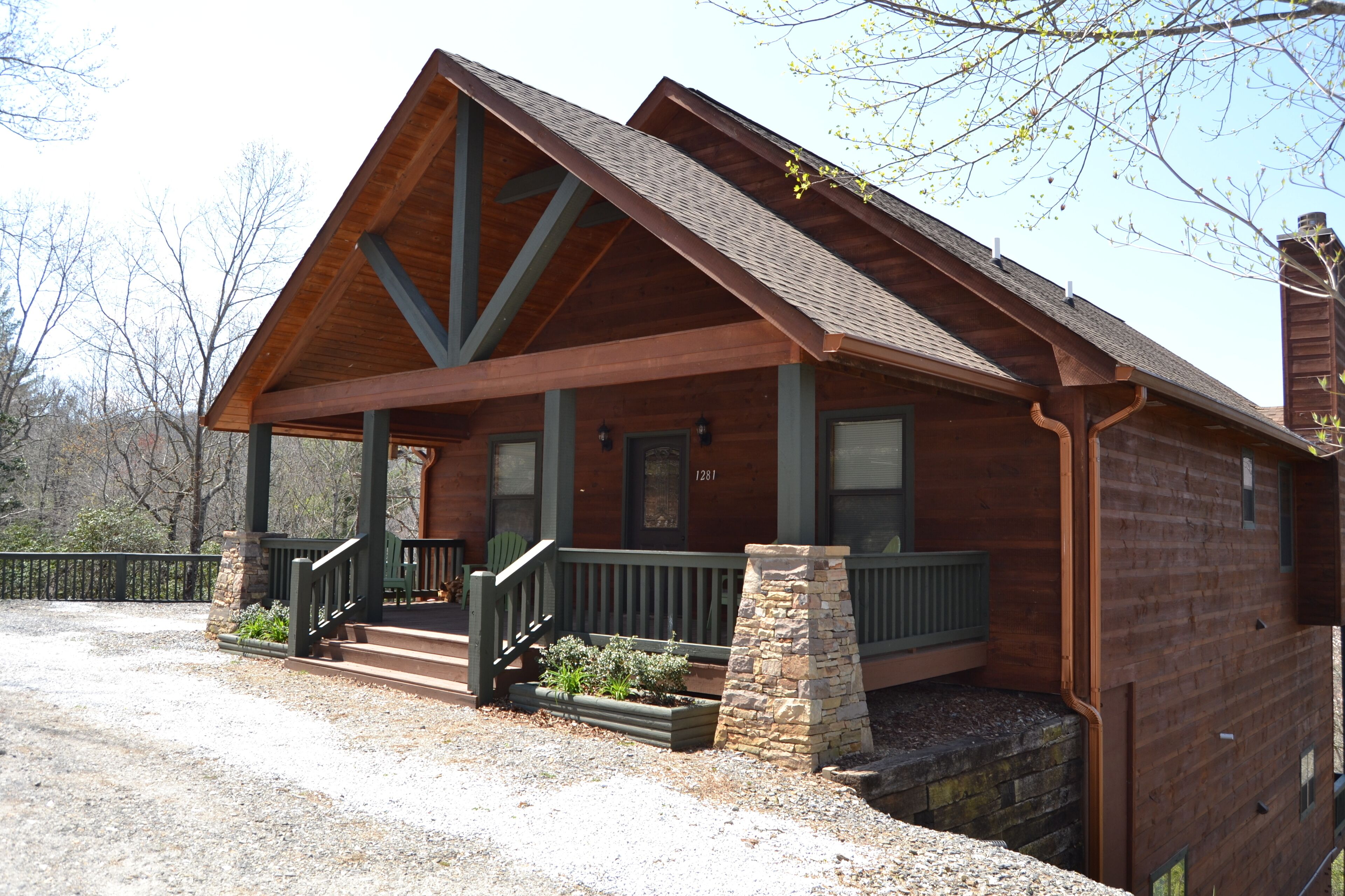 A wooden cabin with a porch, stone steps, and a chimney.