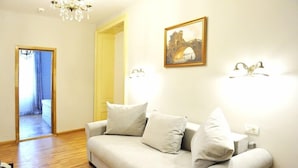 A living room with a sofa, a chandelier, a framed picture, and a doorway leading to another room. - Safrano (Brasov)