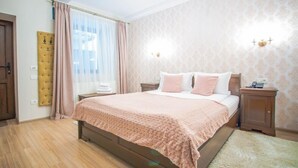 A bedroom with a wooden bed, a nightstand, a wall-mounted lamp, and a window with sheer curtains. - Safrano (Brasov)