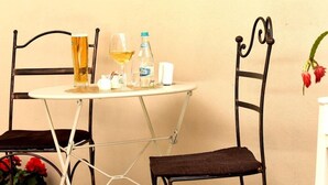 A small round table with a white surface, two metal chairs with dark brown cushions, and a bottle of water. - Safrano (Brasov)