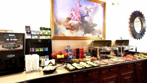 A buffet setup with various food items, a coffee machine, condiments, and a painting on the wall. - Safrano (Brasov)