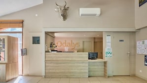 Een receptiegedeelte met een houten receptiebalie, een stierenhoofd decoratie en een bord met de tekst 'Odalys'.