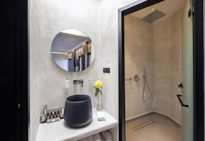 Un bany modern amb un mirall rodó gran, un lavabo negre i una zona de dutxa.