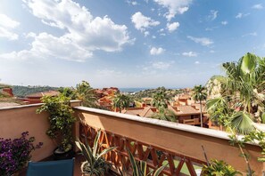 A balcony with a view of a coastal town, palm trees, and a clear sky. - SR Penthouse with sea views (Marbella)