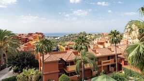 Zona residencial costera con edificios de tejas color terracota, palmeras y vistas al mar.