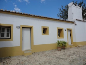 A building with a white facade and yellow trim, featuring a door, windows, and a chimney. - Monte DA Amoreira (Elvas)