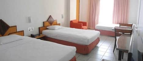 Une chambre d’hôtel avec deux lits simples, un bureau, une chaise et une fenêtre avec des rideaux.