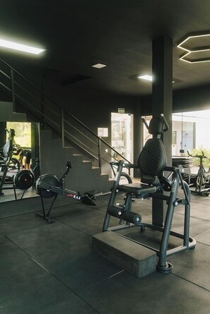 Un gimnasio con equipo de ejercicio, una escalera y una ventana con luz natural.