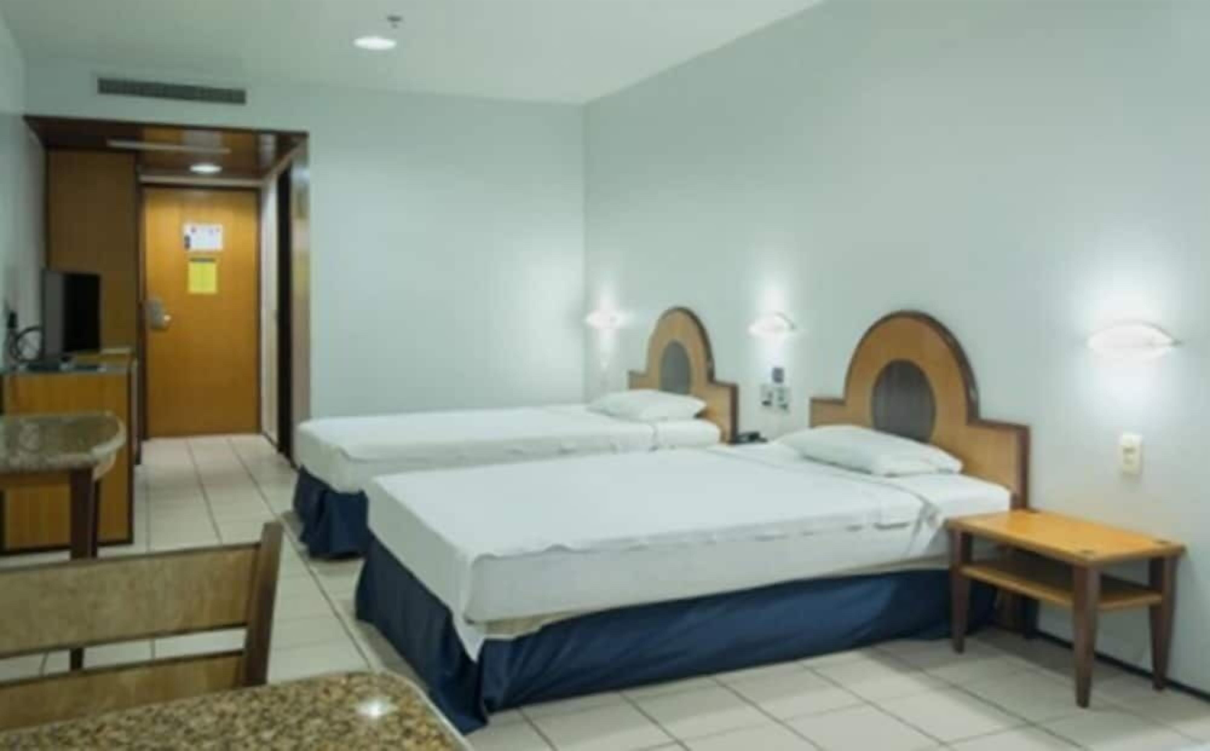 Une chambre d’hôtel avec deux lits, une petite table, une chaise et un bureau avec un ordinateur.