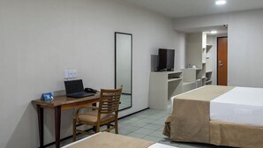 Habitació d'hotel amb escriptori, cadira, portàtil, televisió i dos llits.