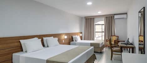 Een hotelkamer met twee bedden, een bureau, een stoel en een raam met gordijnen.