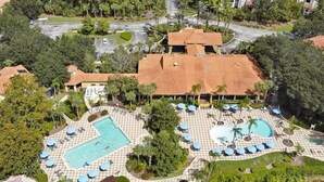 Eine Luftaufnahme eines Resorts mit mehreren Schwimmbecken, Liegebereichen und üppiger Bepflanzung.