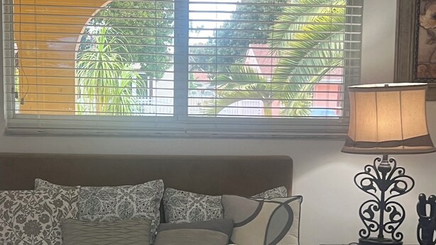 A neatly made bed with patterned bedding, a bedside lamp, and a window with blinds. - Cozy Private Room 2 - Your Quiet Downtown Miami Getaway (Miami)