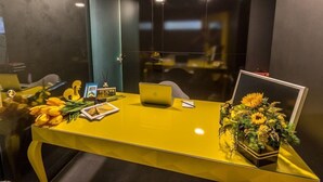 A yellow desk with a laptop, a framed picture, a vase of sunflowers, and a bouquet of yellow flowers. - RM Guest House The Experience (Setubal)