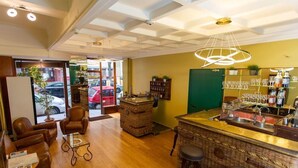 A bar area with wicker furniture, a counter with a sink, and a view of the street outside. - Hotel de la Marne (Lyon)