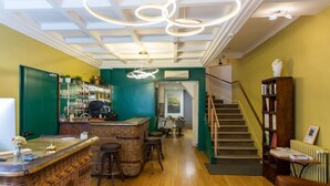 A bar area with wicker furniture, a staircase, and a bookshelf. - Hotel de la Marne (Lyon)
