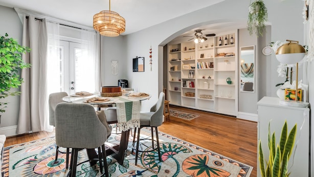 A dining area with a round table, chairs, and a patterned rug.