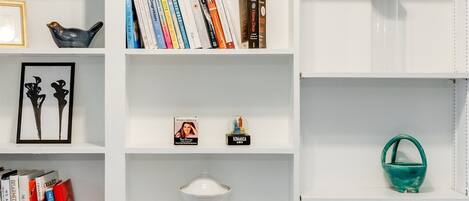 A white bookshelf with various items including books, decorative objects, and wine bottles.