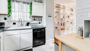 A modern kitchen with white cabinetry, a built-in dishwasher, and a wooden dining table.
