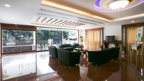A modern hotel lobby with a glass partition, seating area, and a television. - Treebo Akshaya Mahal Inn (Mysore)