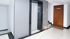 Un couloir doté d’un ascenseur moderne et d’une porte en bois portant l’inscription « SALLE DE RÉUNION ».