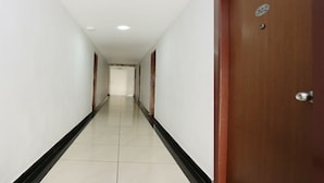 Un long couloir étroit aux murs blancs et au plintheur noir, qui mène à une porte portant le numéro 302.
