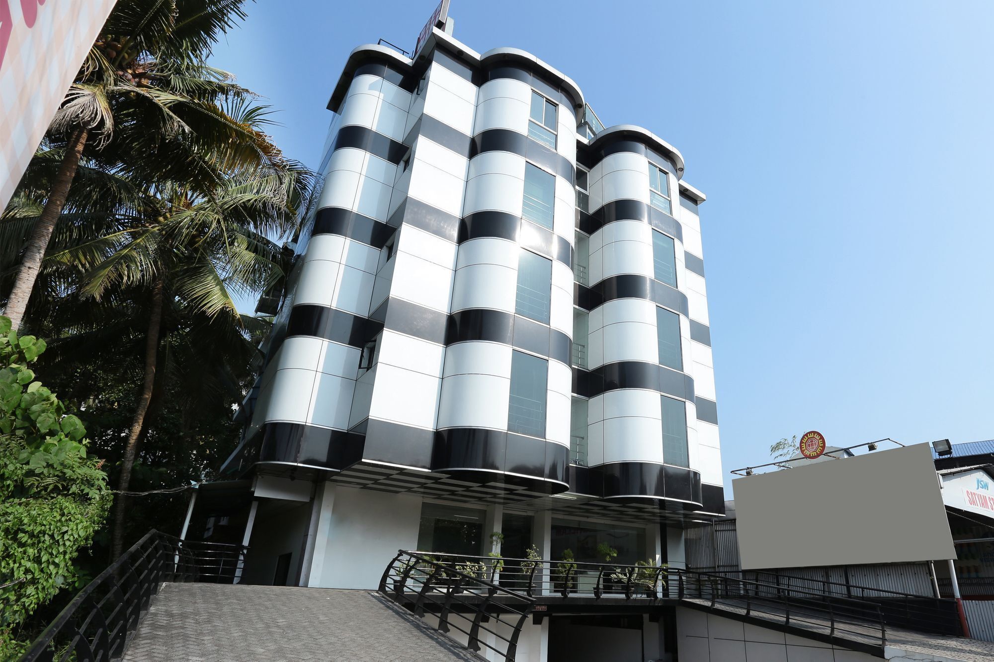 A modern building with a unique cylindrical design, featuring multiple balconies and a prominent entrance with a glass facade.