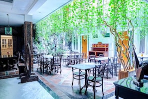 A restaurant with outdoor seating, stone walls, and hanging greenery. - Boutique B21 Malang, Azana Hotels Collection (Malang)