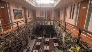 Un restaurant avec un plafond haut, des rampes en bois et des tables disposées autour d’un espace central.