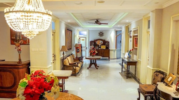 Un hall d’hôtel spacieux, agrémenté d’un lustre, d’un canapé, d’une table basse et d’un coin repas.