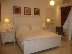 A neatly made bed in a hotel room with a white headboard, two bedside tables with lamps, and three framed pictures on the wall. - Boutique B21 Malang, Azana Hotels Collection (Malang)